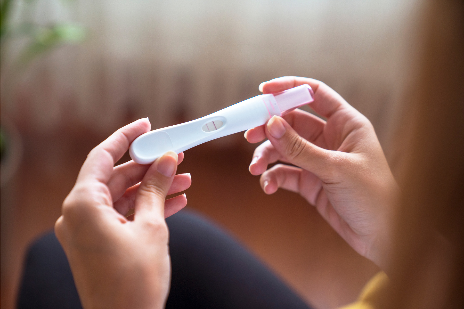 Image of hands holding a positive pregnancy test.